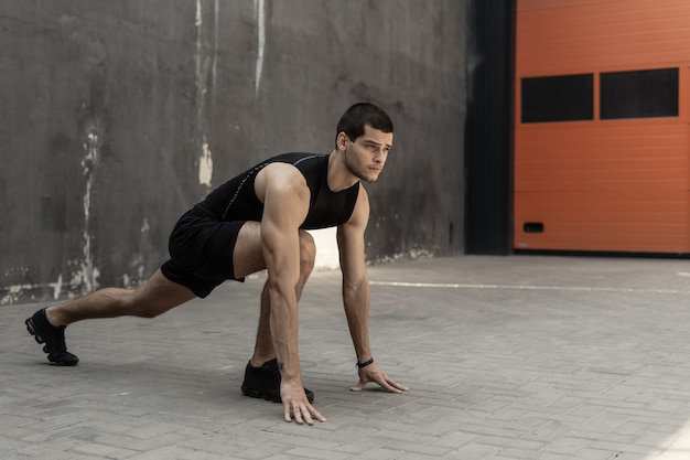 Sportsman starting his sprint on a gray industrial wall