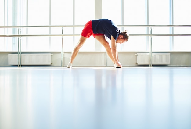 Sportsman stretching his legs before training session