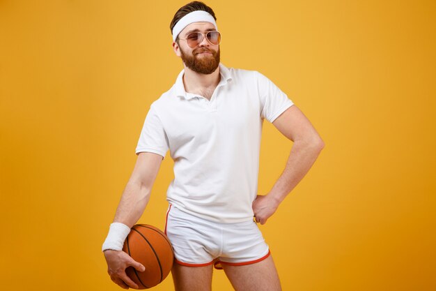 Спортсмен в солнцезащитных очках держит баскетбол