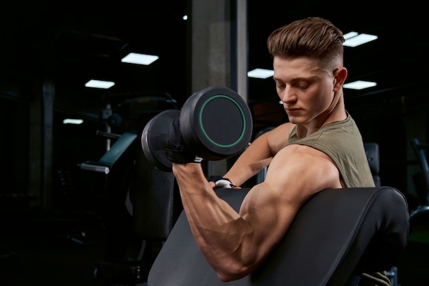 Sportsman training biceps with dumbbell.