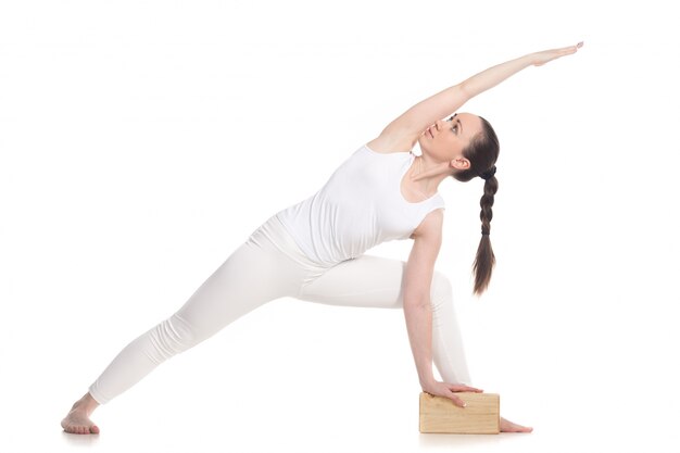 Sportswoman doing yoga exercises with a wooden block