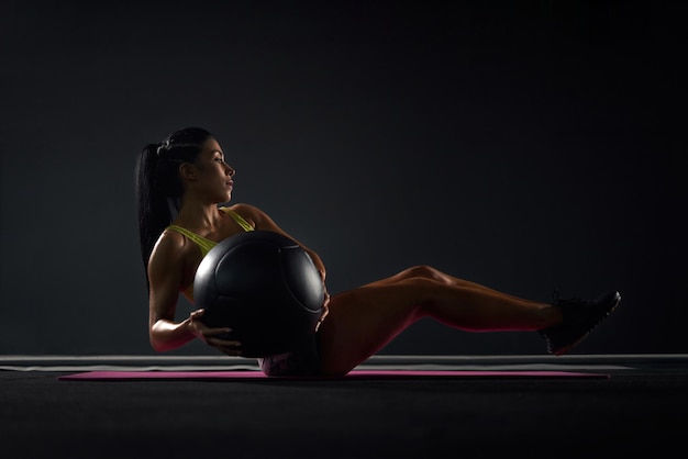 Sportswoman training abs with ball in gym