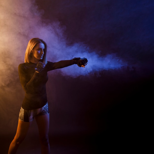 Sportswoman training box in dark studio