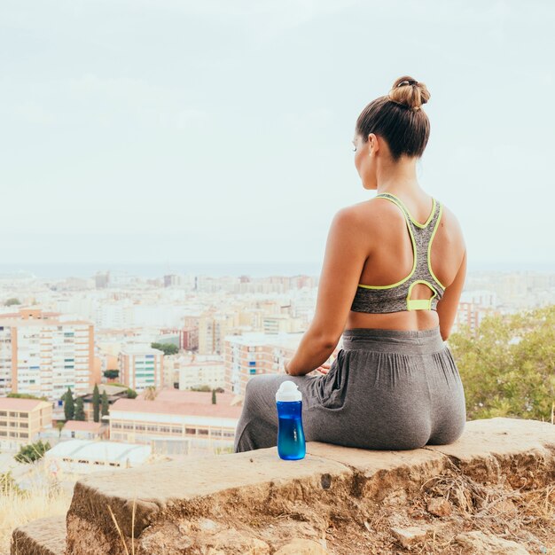 Спортсменка, бутылка воды и город