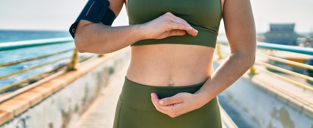 Free photo sportswoman wearing sportswear with hands on stomach at the city.