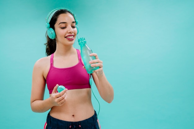 Free photo sportswoman with earphones drinking water