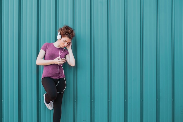 Sportswoman with headphones and phone on street