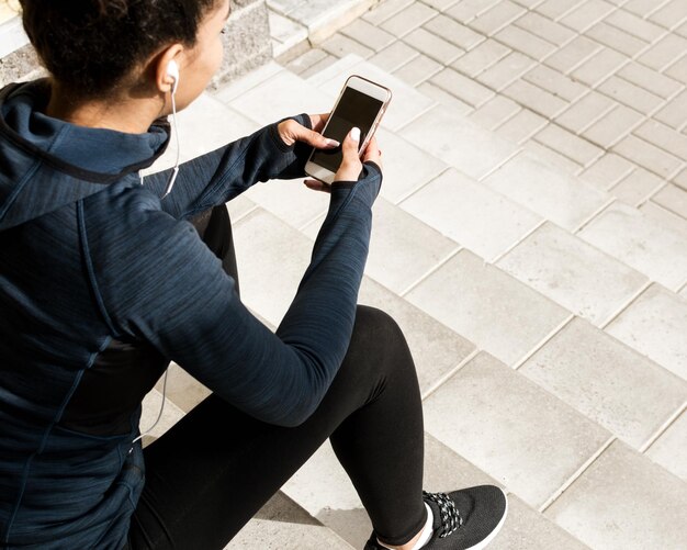 Sportswoman with mobile phone relaxing during training