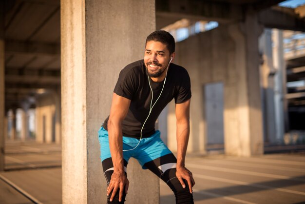 Sporty attractive male listening to music and smiling on training