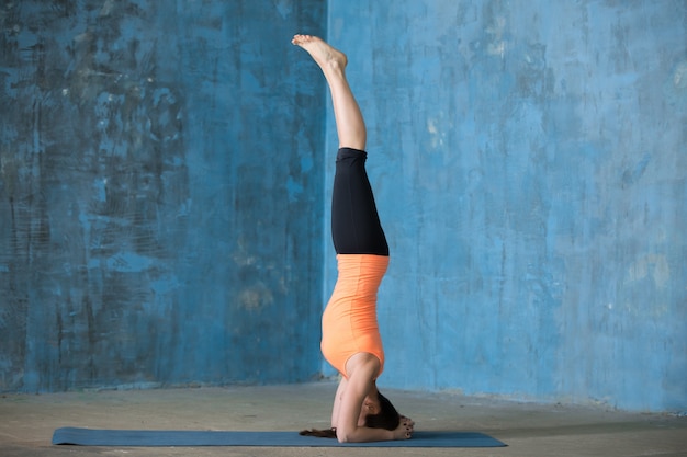 Sporty beautiful young woman doing headstand