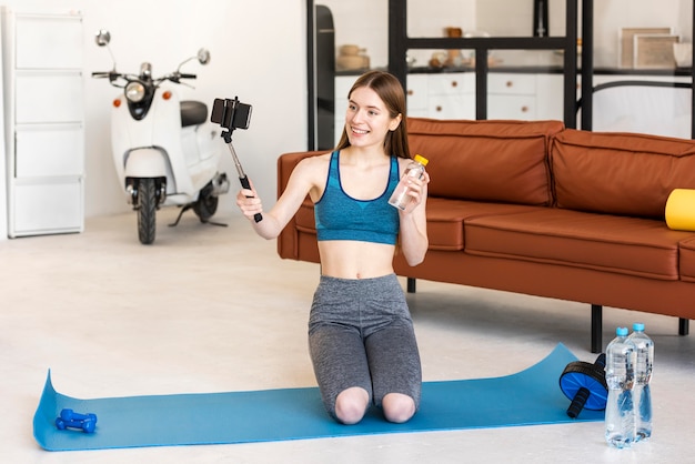 Sporty blogger holding bottle of water and using smartphone