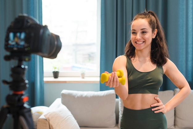 Sporty blogger showing dumbbells to camera