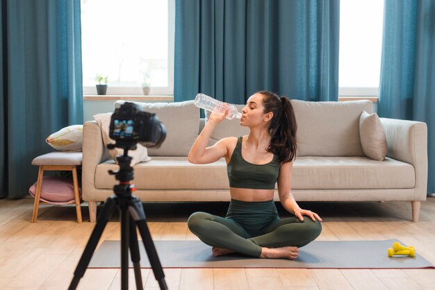 Sporty blogger sitting in lotus position drinking water