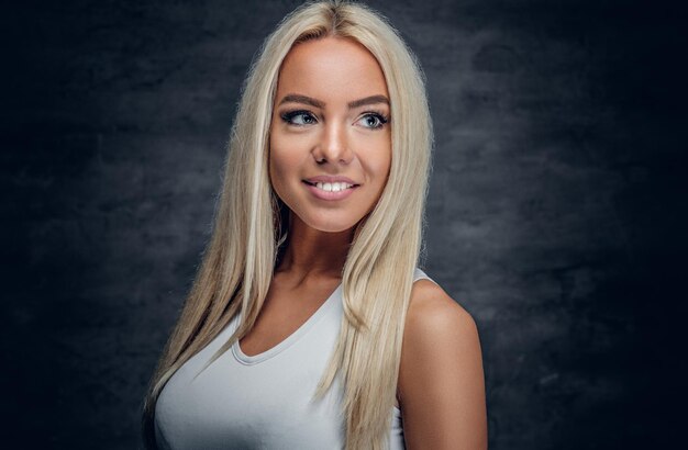 Sporty blonde female in white t shirt on grey background.