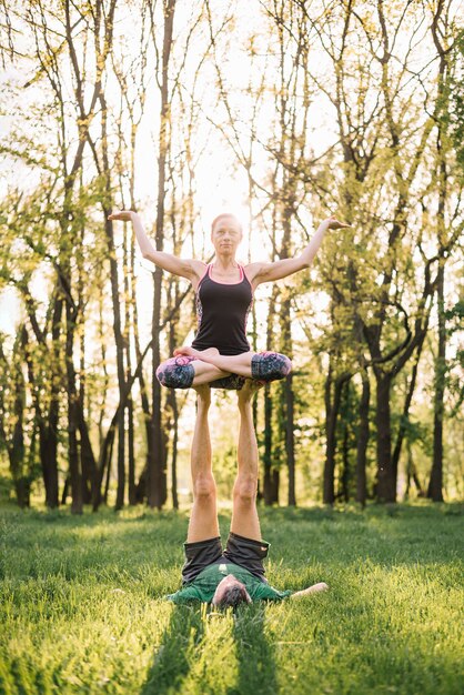 Sporty couple doing acroyoga exercises on green glassy land