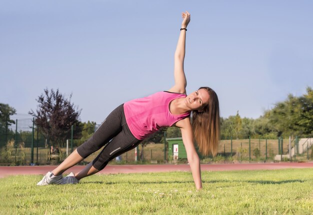 Спортивная женщина делает тренировку в парке - концепция спорта и здорового образа жизни