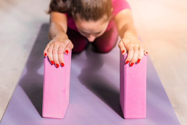Бесплатное фото Спортивная женщина фитнес, практикующих йогу с розовыми блоками на матах