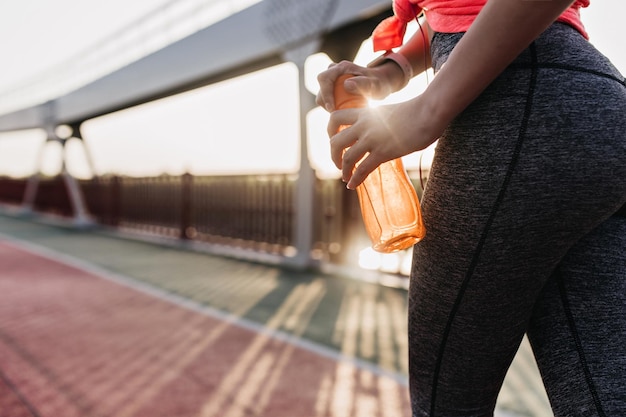 長いマラソンの後に水を飲むスポーティな女の子スポーツ競技の準備をしている格好良い女性モデル