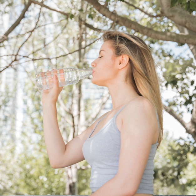Спортивная девушка питьевой воды в парке