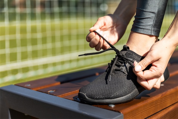 Free photo sporty girl lacing her sneakers on a bench