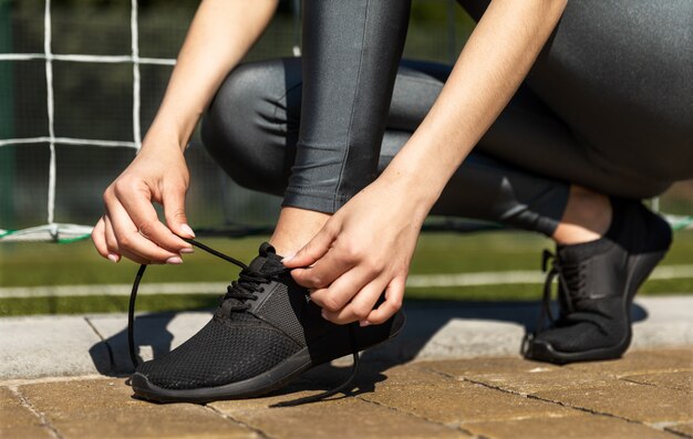 Sporty girl lacing her sneakers outdoor