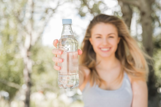 Бесплатное фото Спортивная девушка показывает бутылку воды