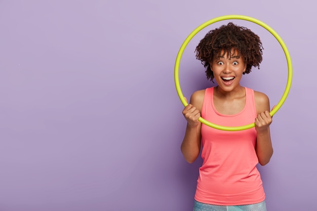 Free photo sporty happy aro woman does exercises with hula hoop, laughs and enjoys rest