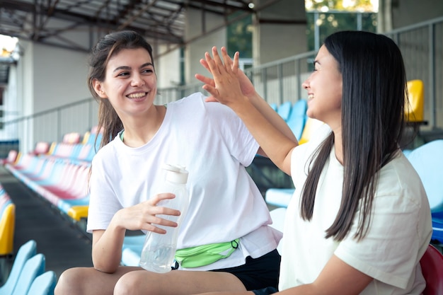 Free photo sporty happy women sitting on the bleachers at the daylight