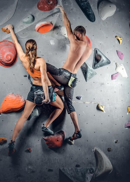 Sporty male and female climbing on a climbing  wall.