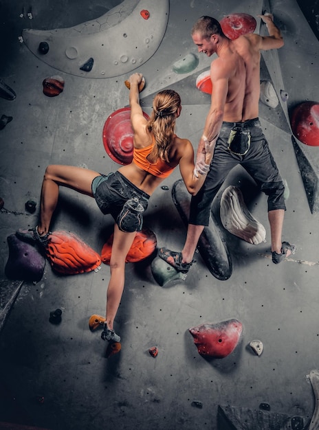 Free photo sporty male and female climbing on a climbing  wall.