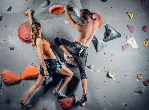 クライミングウォールに登るスポーティな男性と女性。