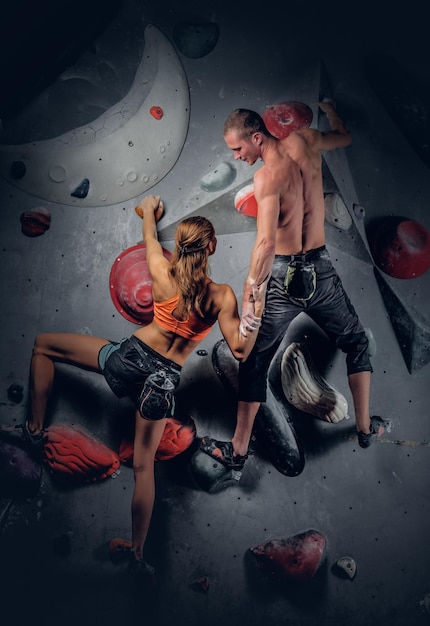 Sporty male and female climbing on an indoor climbing wall.