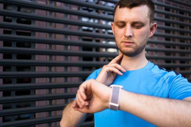 Sporty man checks his pulse during city workout