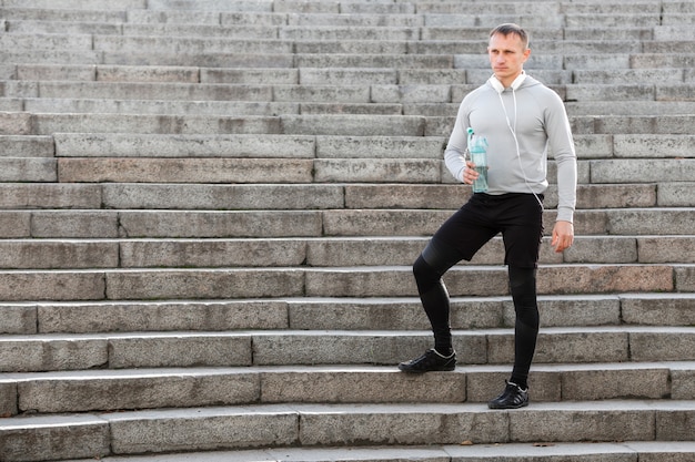 Спортивный человек держит бутылку воды на лестнице