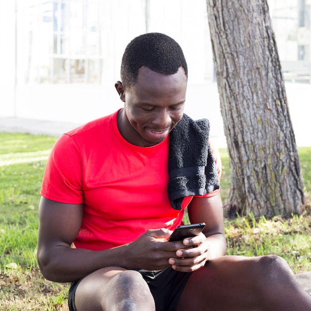 スマートフォンを見て公園のスポーティな男