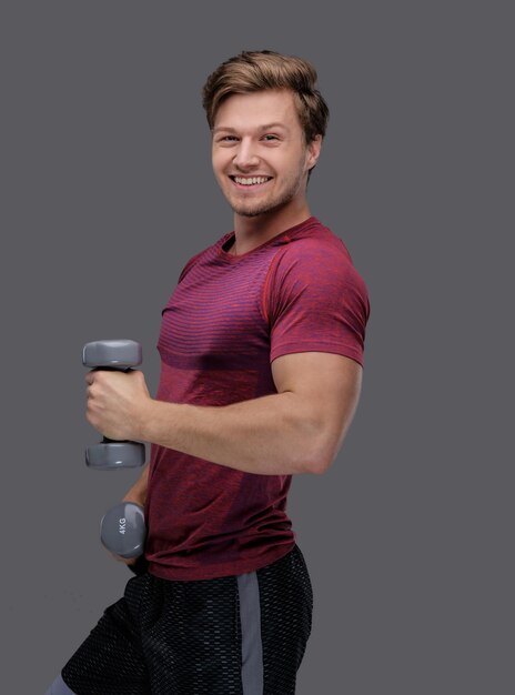 Sporty man in a red t shirt holds dumbbells.