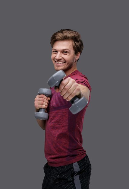 Sporty man in a red t shirt holds dumbbells.