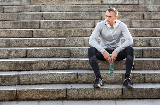 Free photo sporty man resting on stairs and looking away