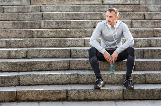 Sporty man resting on stairs and looking away
