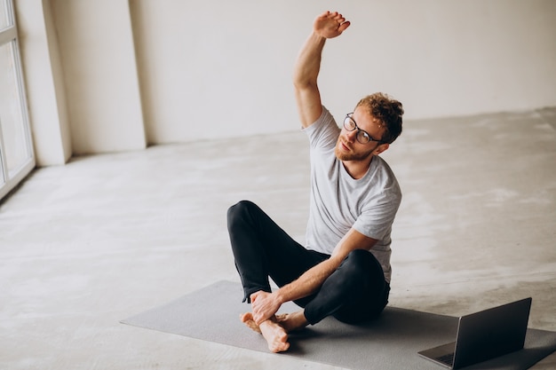 Sporty man watching tutorials and practicing yoga on the mat