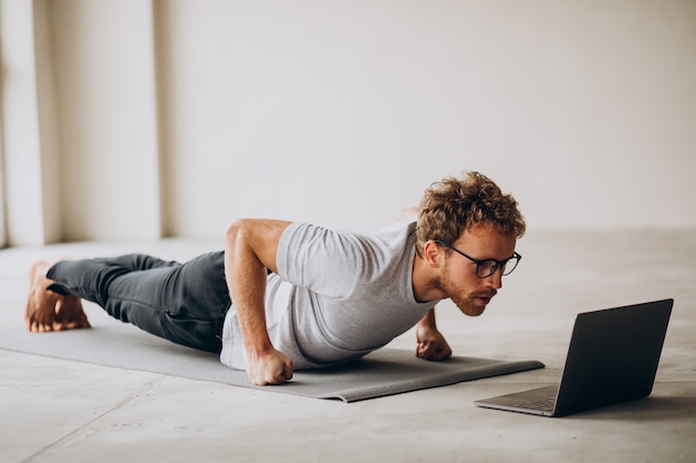 Sporty man watching tutorials and practicing yoga on the mat