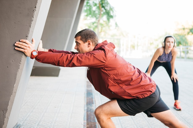 Sporty man and woman stretching in urban environment