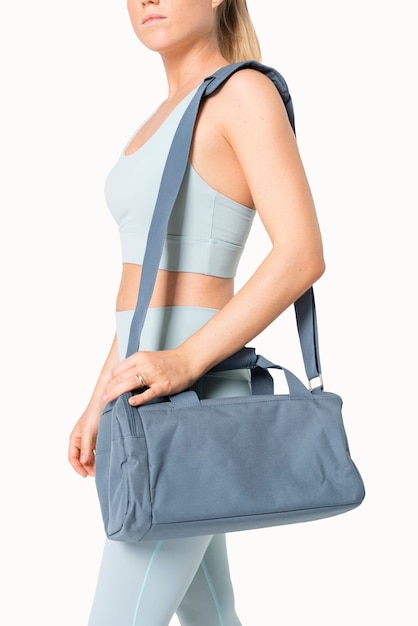 Free photo sporty woman carrying blue duffle bag gym essentials studio shoot