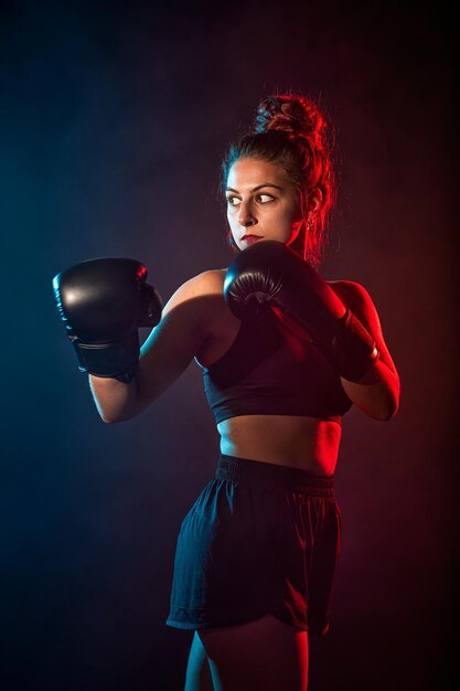 Sporty woman doing boxing exercises  making direct hit. photo of young girl. strength and motivation.