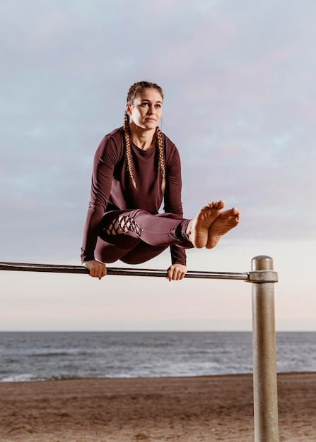 Бесплатное фото Спортивная женщина делает фитнес-упражнения снаружи на пляже