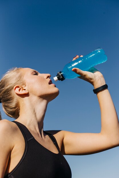 Sporty woman drinking at the beach