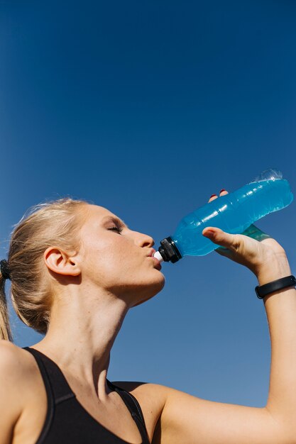 Sporty woman drinking at the beach