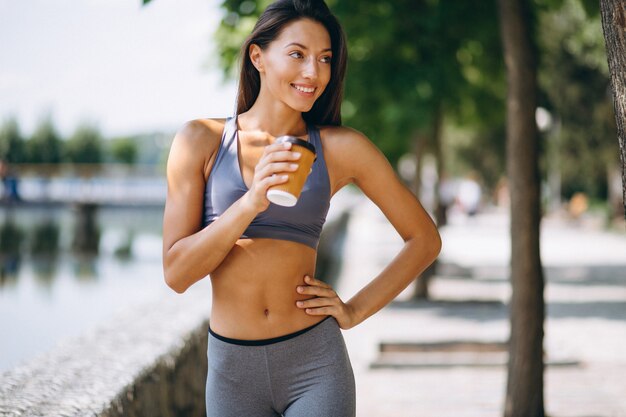 公園の中でコーヒーを飲むスポーティな女性