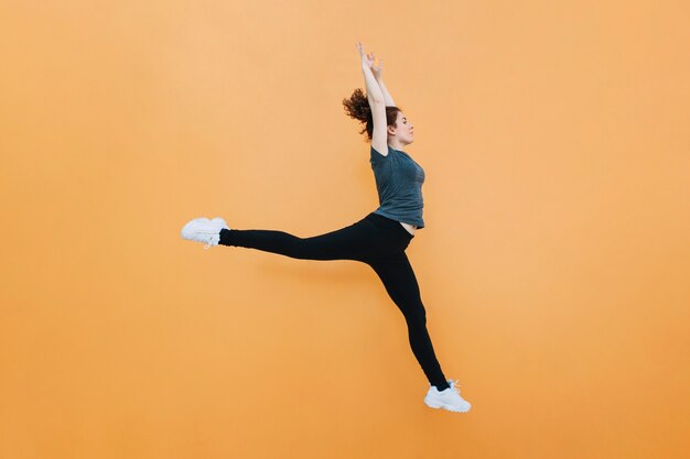 Спортивная женщина прыгает на желтой стене