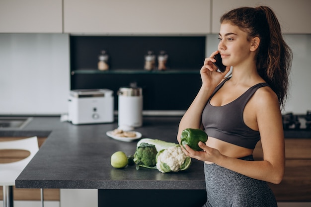 Sporty woman at kitchen using mobile phone